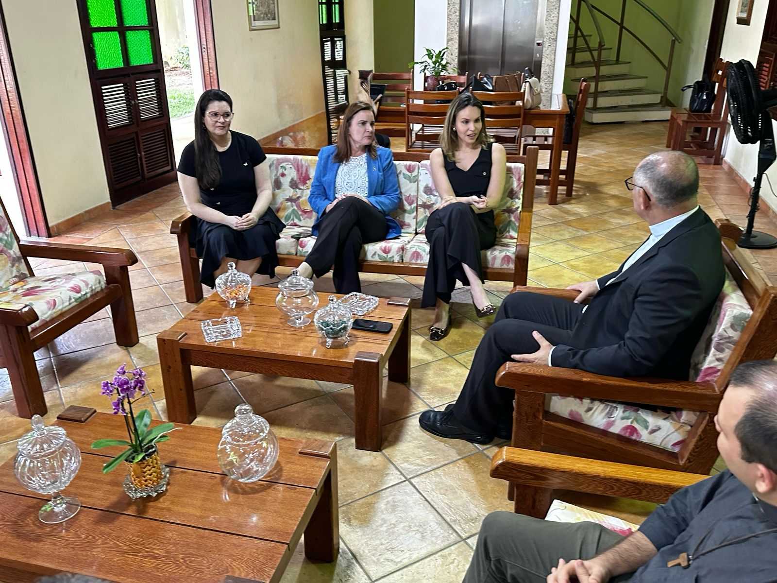a foto mostra um grupo de pessoas sentadas em poltronas durante uma reunião